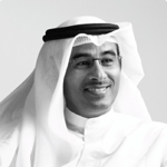 Man in Middle Eastern attire smiles against plain background.