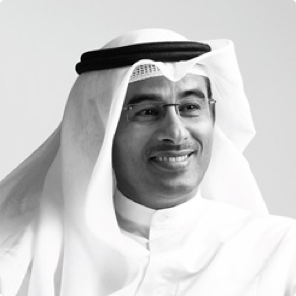 Man in Arab headdress smiling slightly, looking to the right.