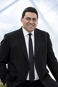 Man in suit posed outside modern building.