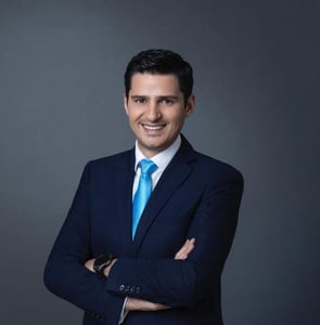 Man in blue suit and tie standing with arms crossed.