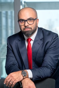 Man in a suit and glasses in an office setting.