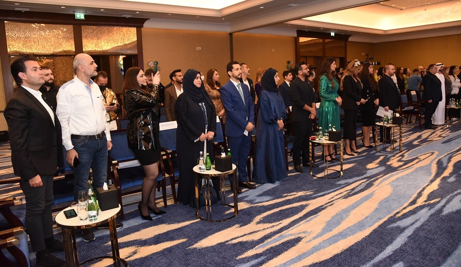 Group of people in business attire in formal hall, taking photos.