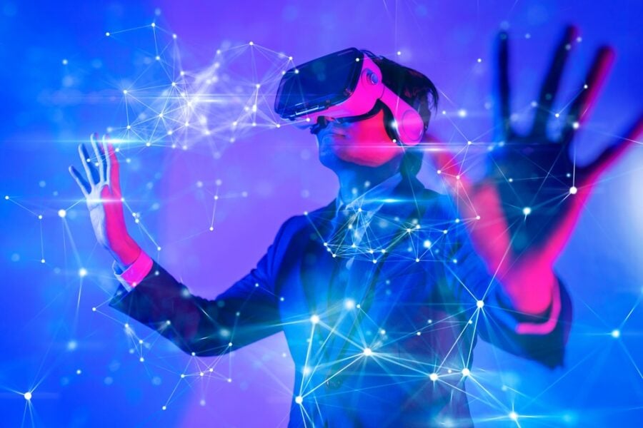 A person wearing a VR headset interacts with a digital network in a blue and pink space.
