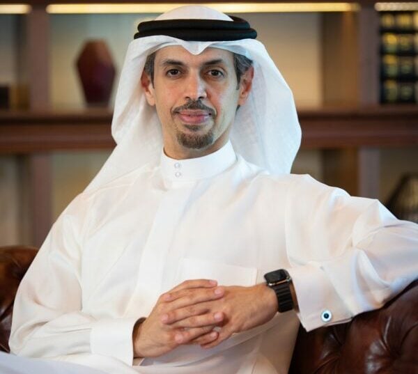 Man in traditional attire seated in a sophisticated room.