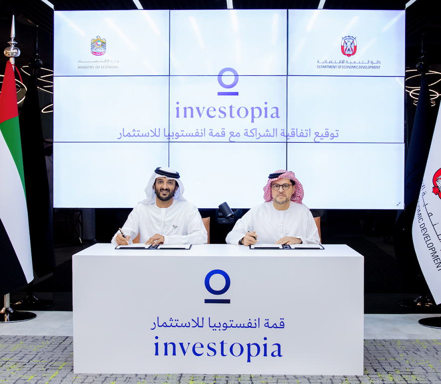 Two men sign an agreement at an Investopia event.
