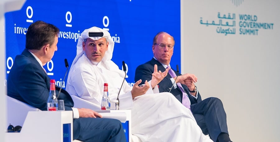 Men in formal attire discuss at the World Government Summit backdrop.