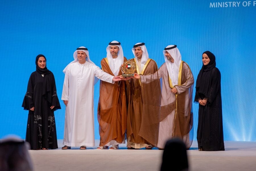 Emirati men present an award to a woman on stage with 