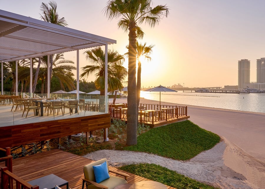 Beachfront restaurant on wooden deck with sunset view.