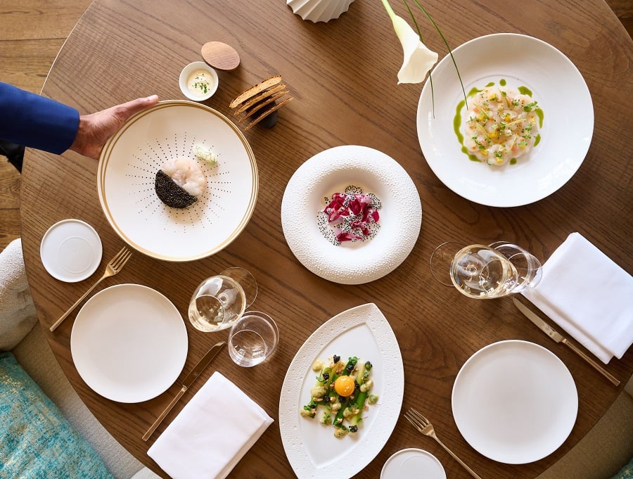 Waiter serves seafood dish with wine glasses.