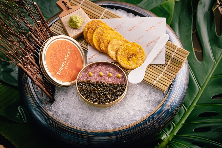 A small bowl of caviar and seafood rests on ice, accompanied by plantain chips.
