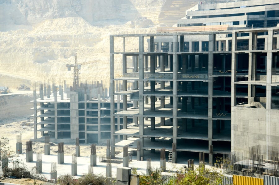 Concrete building frame under construction with crane.
