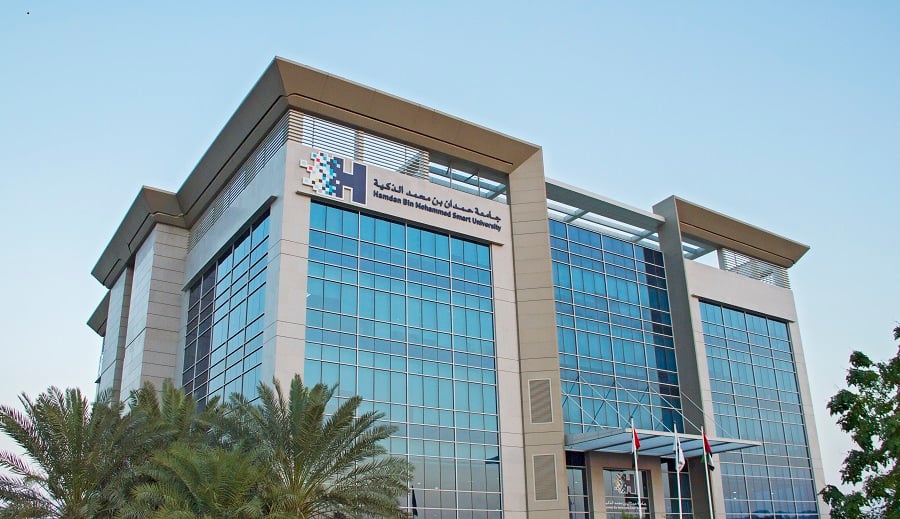 Modern university building with palm trees in the foreground.