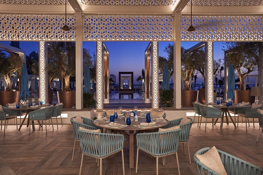 Dining table at an outdoor restaurant with a city view at twilight.