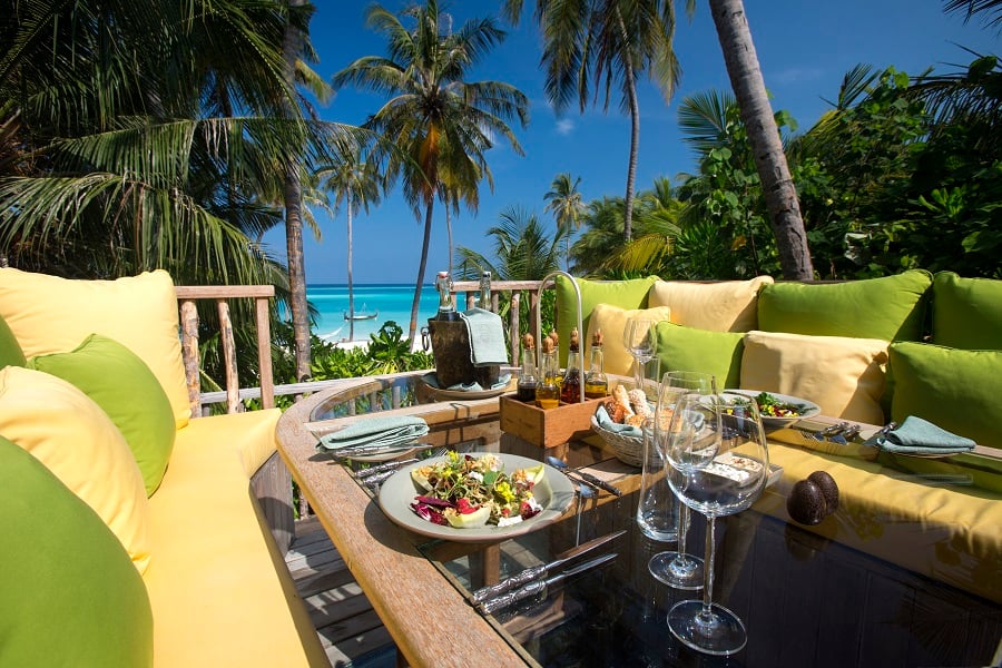 Meal served on table overlooking tropical beach setting.