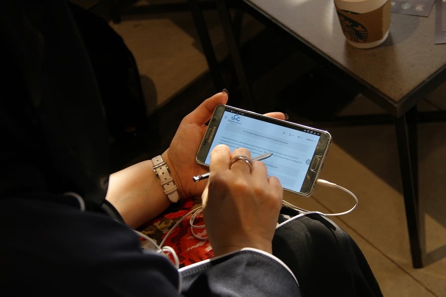 Person writing on Samsung smartphone in cafe.