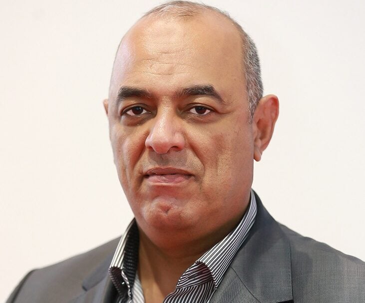 Serious man in gray suit against a white backdrop.