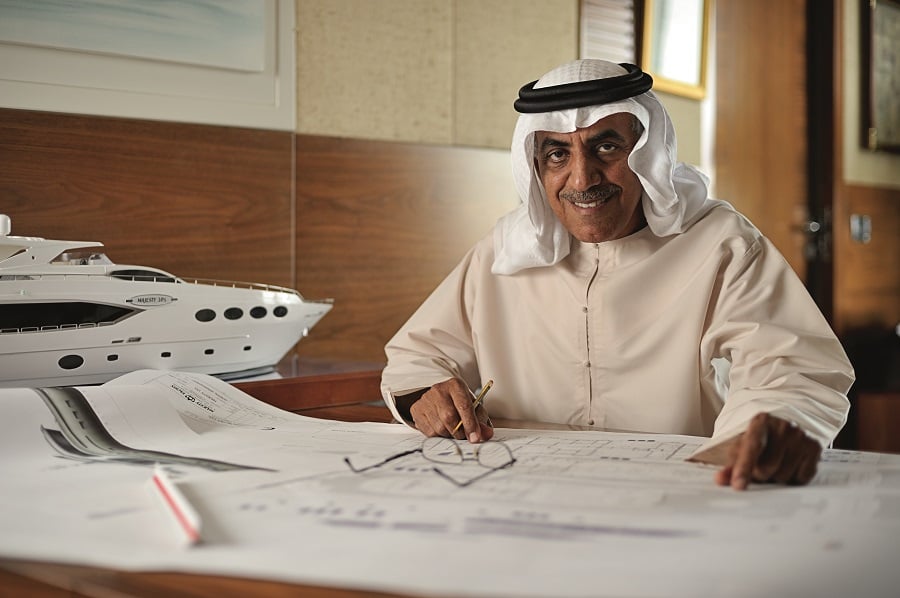 Emirati man reviewing blueprints with a yacht model nearby.