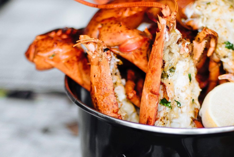 Lobster halves served in black container with lemon.