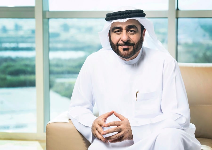 Man in white thobe sitting in armchair near window with outdoor view.