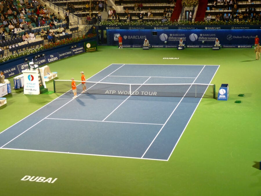 Tennis court with two players near net in ATP World Tour match.