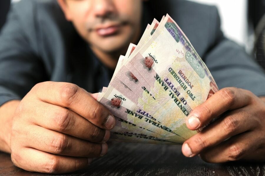 Hands holding Egyptian 200-pound notes.