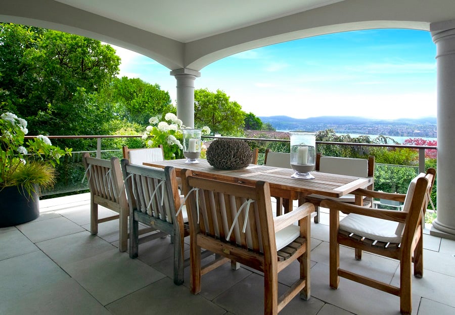 Wooden patio dining set overlooking a lake and hills.