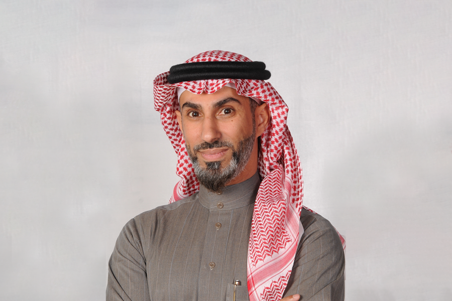 Man in a gray thobe and keffiyeh with arms crossed.