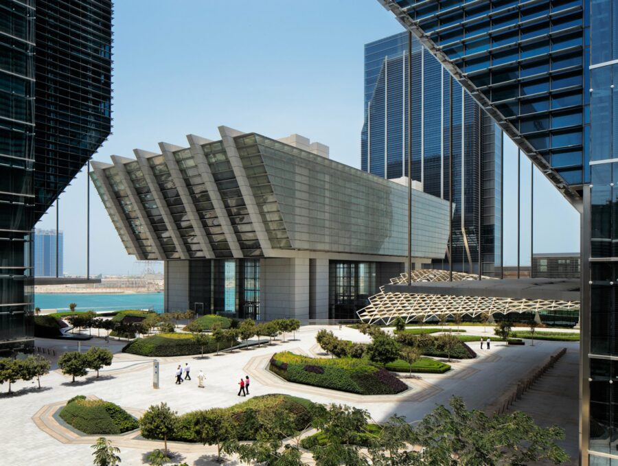 Modern building with plaza and skyscrapers nearby.