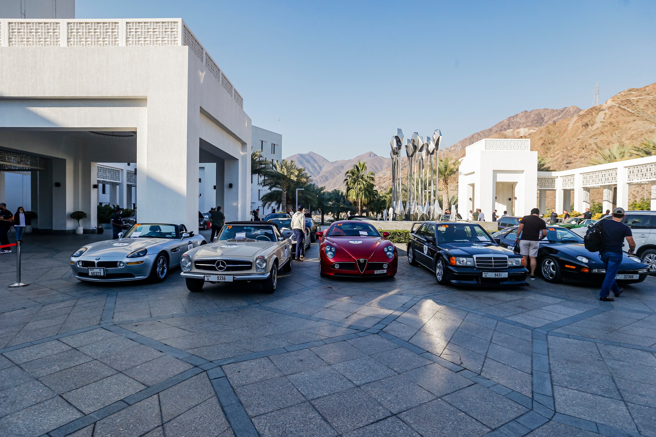 Classic cars parked near modern buildings.