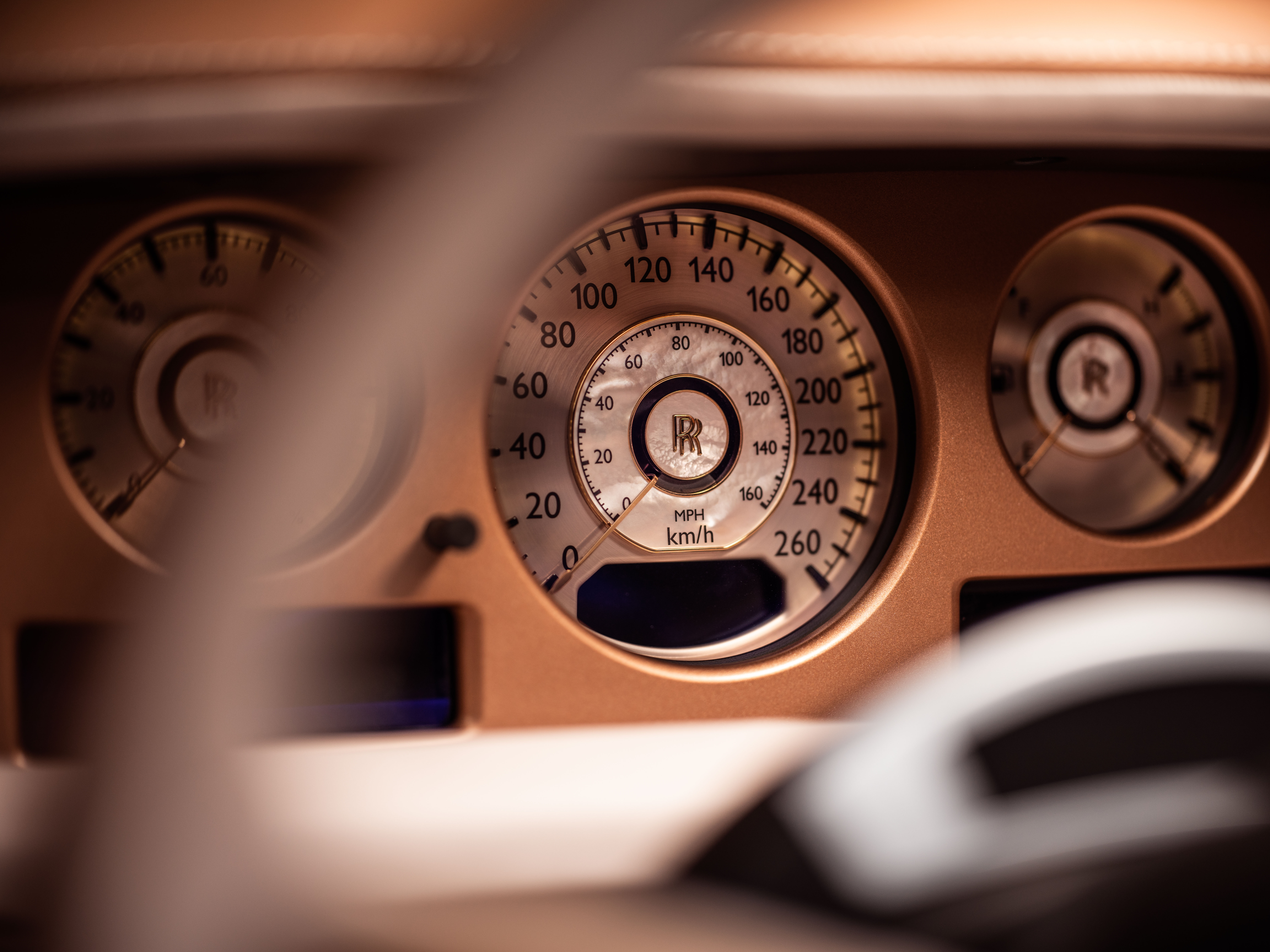 Speedometer showing zero mph/kmh on a rose-gold dashboard.