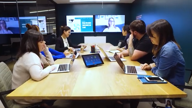 People work on laptops during video conference in modern office.