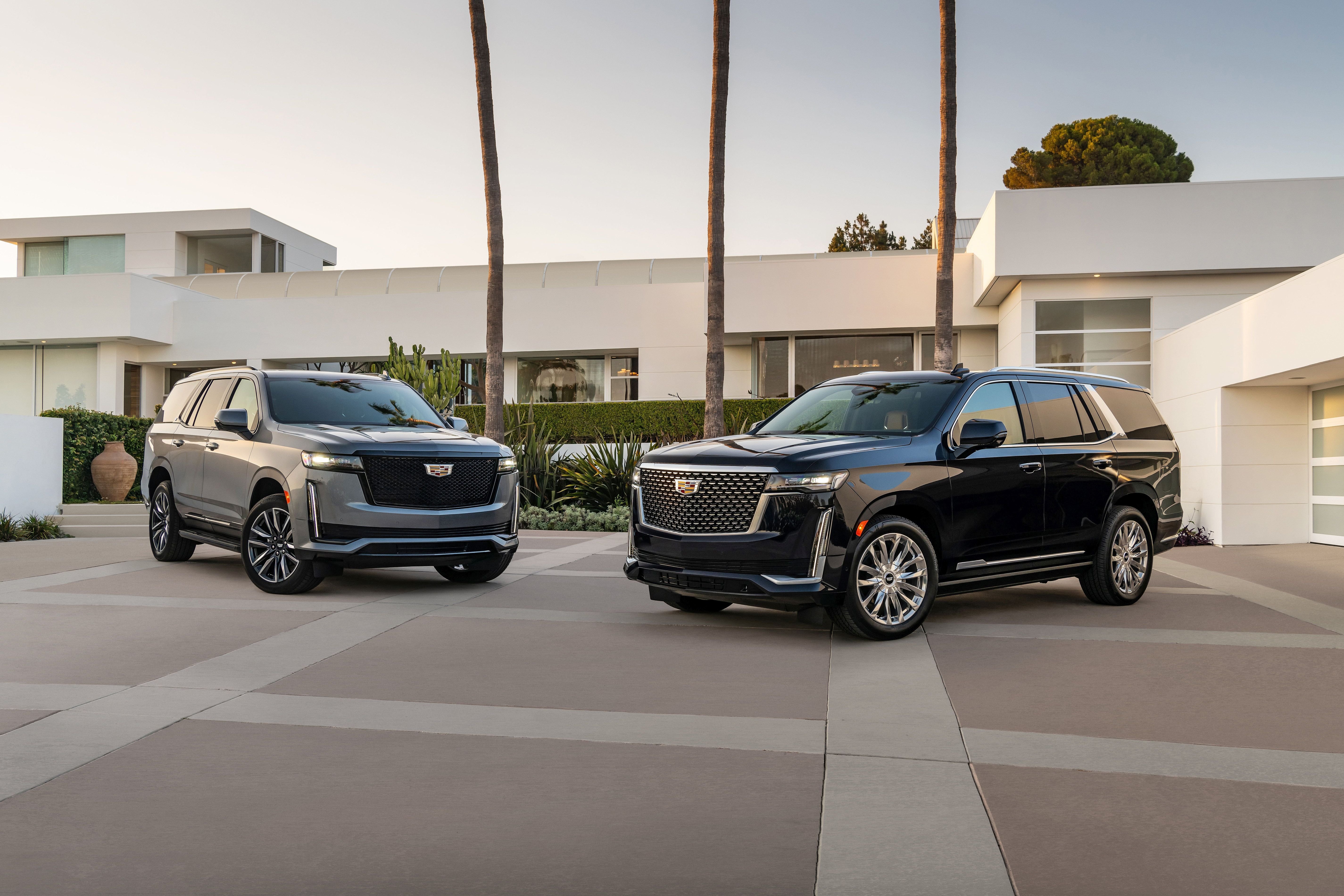 Two Cadillac Escalades parked in front of a modern white house.