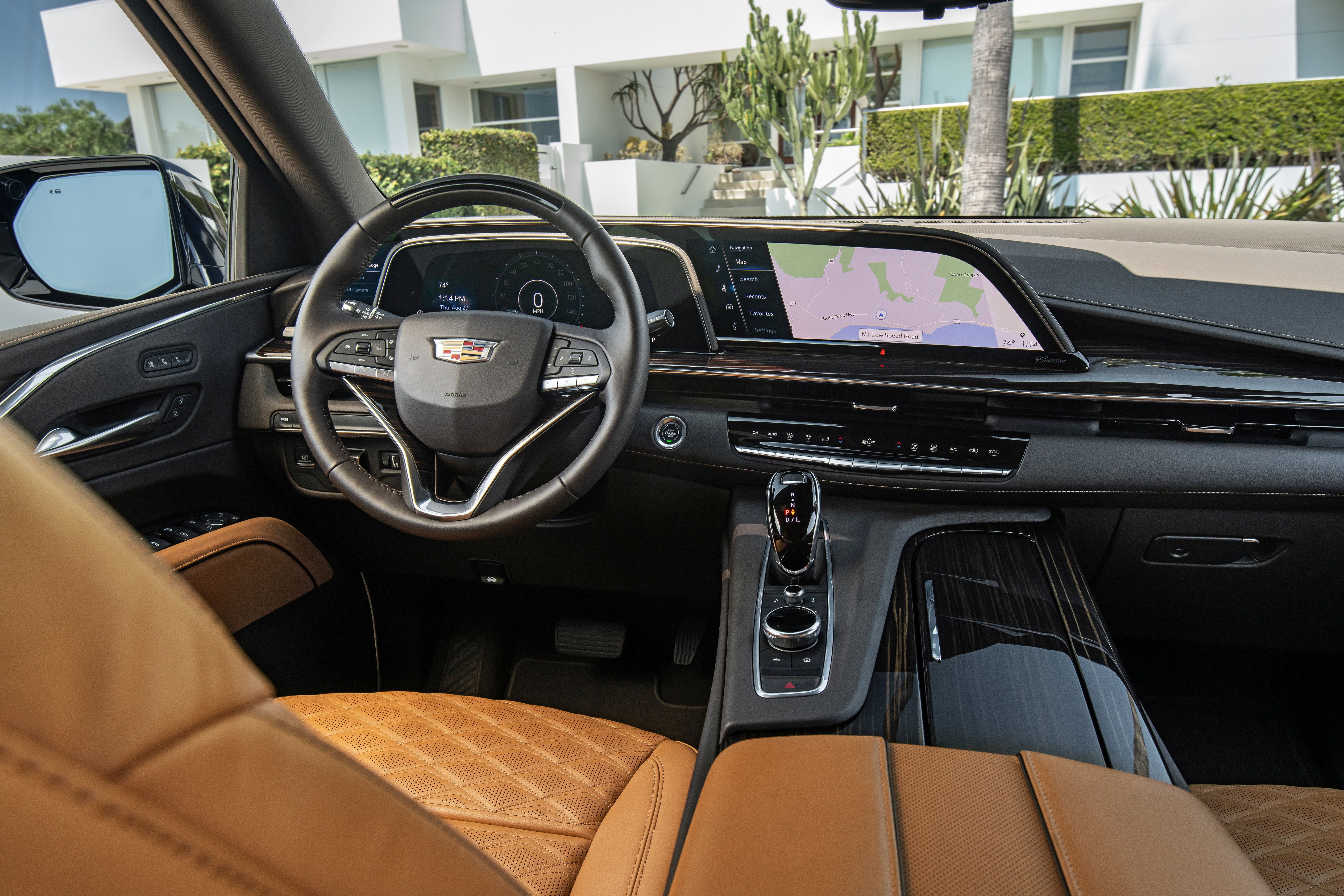 Cadillac Escalade interior with navigation screen outside modern house.