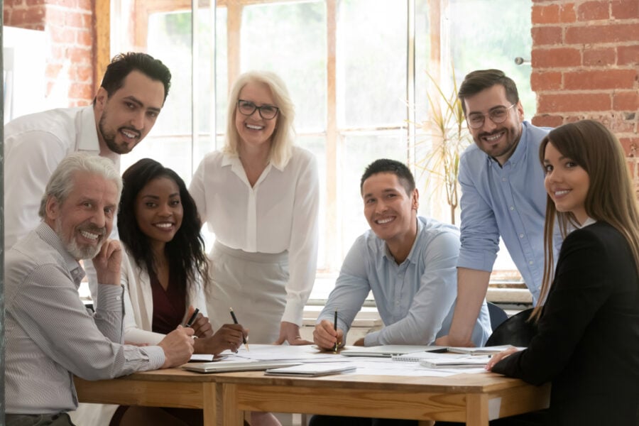 Diverse coworkers smiling while working together in a bright office.