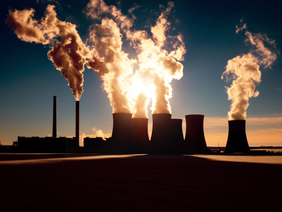 Cooling towers emitting smoke at sunset.