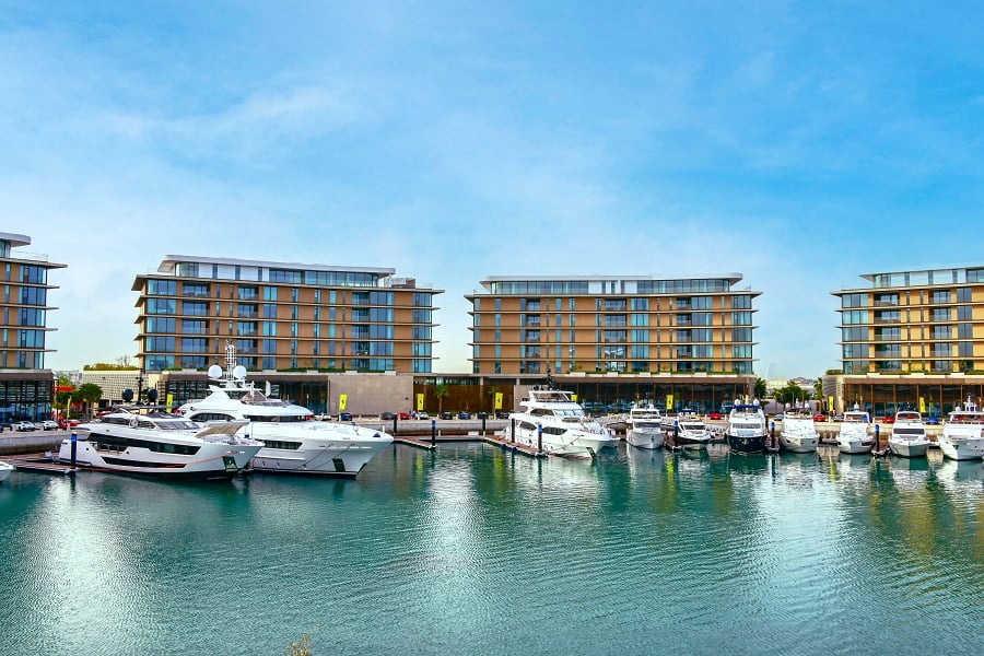 Luxury yachts docked at a marina with modern apartment buildings.