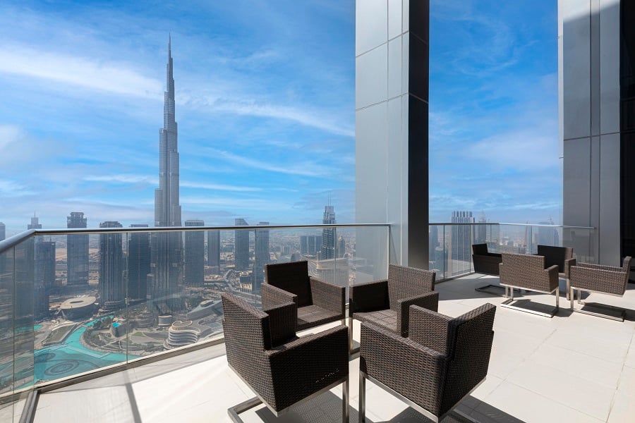 Wicker chairs on a balcony with a view of Burj Khalifa.