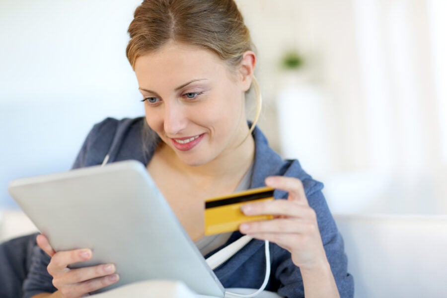 Woman using a tablet to make an online purchase while holding a credit card.