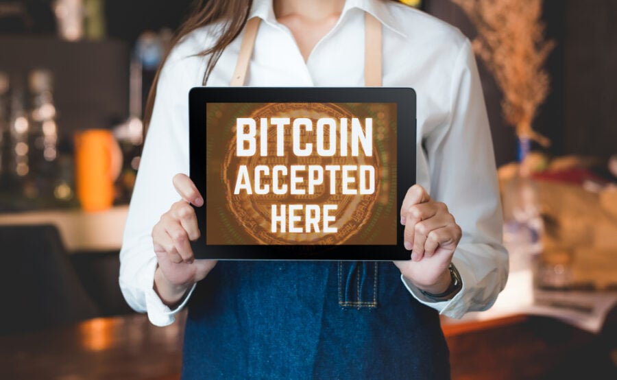 A tablet displaying "BITCOIN ACCEPTED HERE" in a cafe.