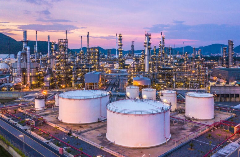 Storage tanks in refinery at twilight with industrial structures.