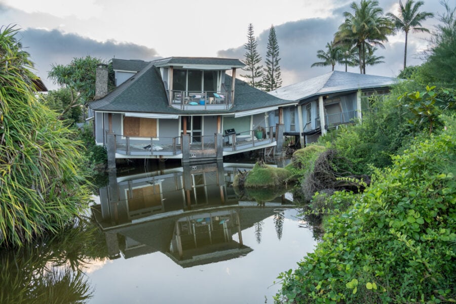 Damaged house reflected in pond.
