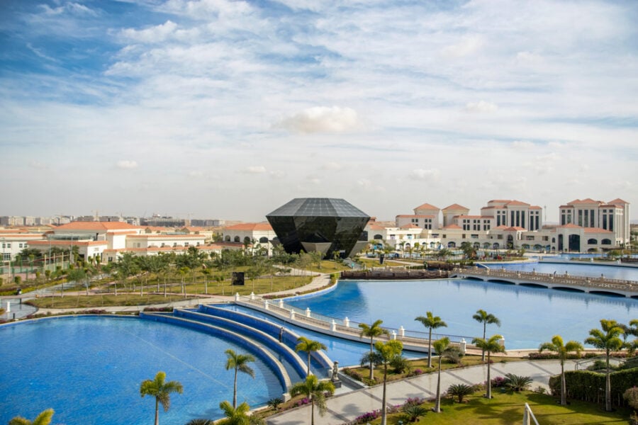 Black diamond-shaped building surrounded by landscaped grounds.