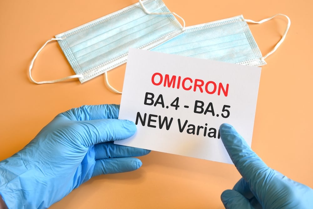 Gloved hands holding "OMICRON BA.4 - BA.5 NEW Variant" paper.