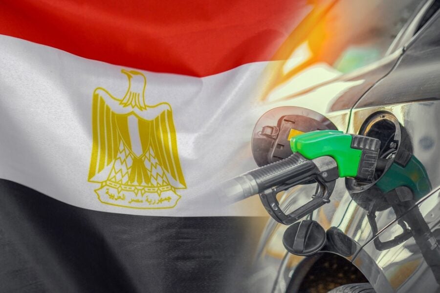 Fuel nozzle in a car tank with the Egyptian flag in the background.