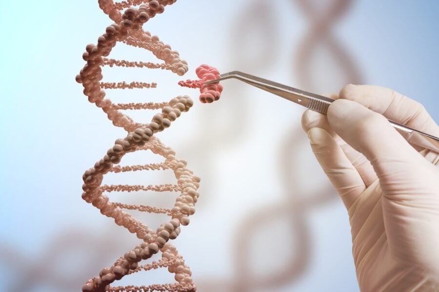 Gloved hand using tweezers to manipulate DNA in a lab.