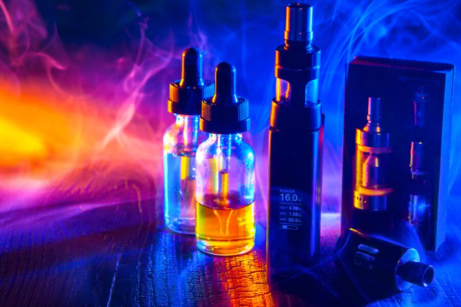 E-liquid bottles and vaping devices surrounded by vapor cloud.