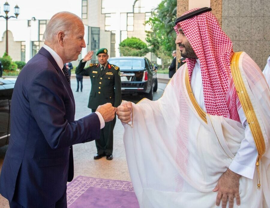 Two men exchanging a fist bump outside a building.