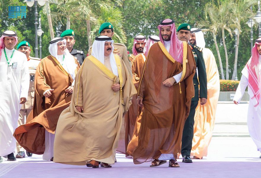 Men in robes walking in procession outdoors at formal event.