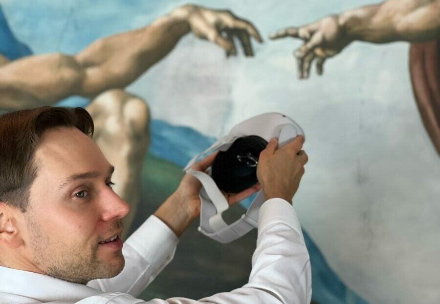 Man holding VR headset in front of a painting.