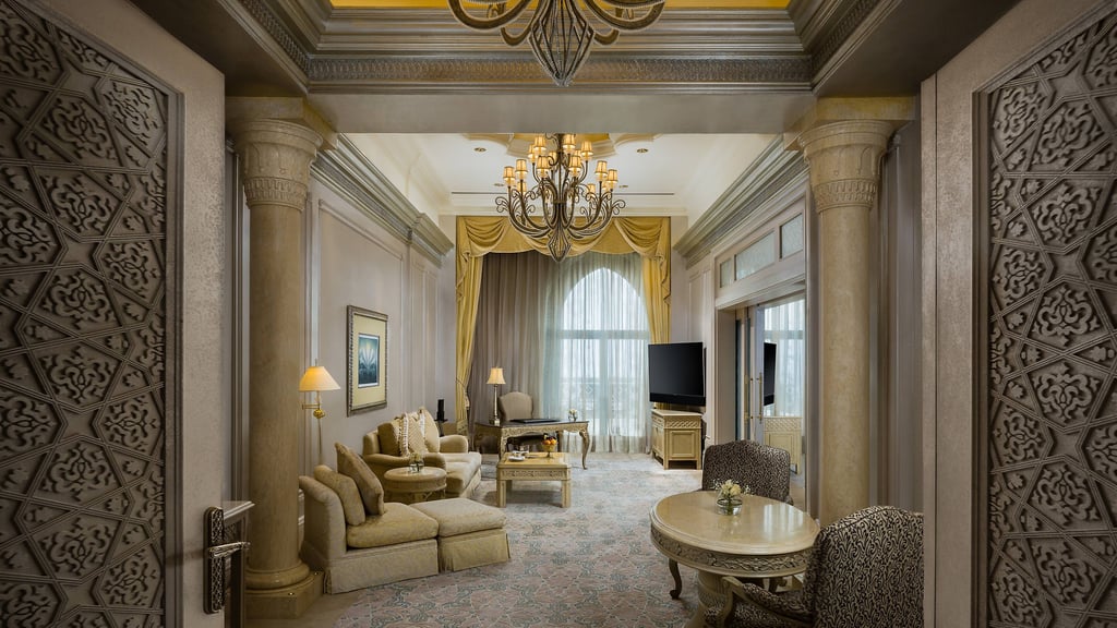 Luxurious suite with beige furniture and a dining area.